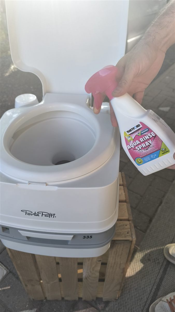 Nettoyage de la cuvette d'un WC chimique avec un spray de rinçage