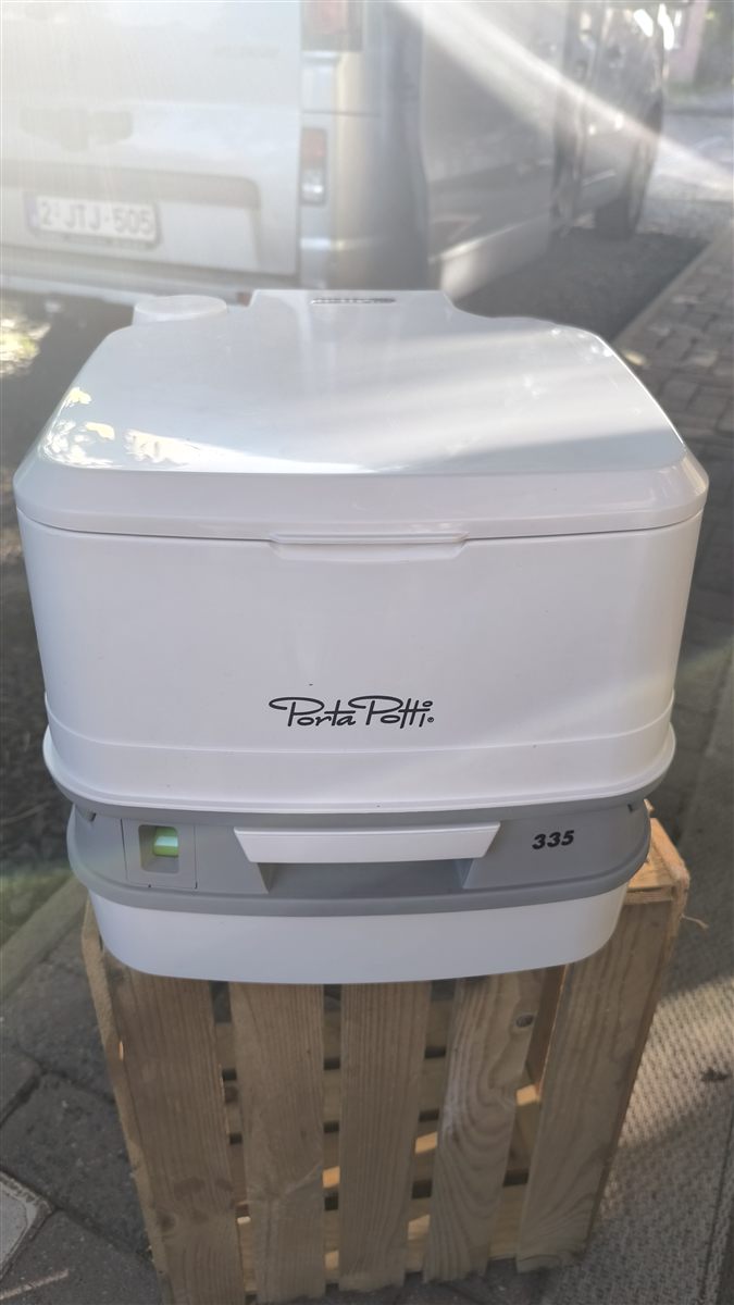WC chimique portable Thetford Porta Potti, prêt à l'emploi devant un van aménagé